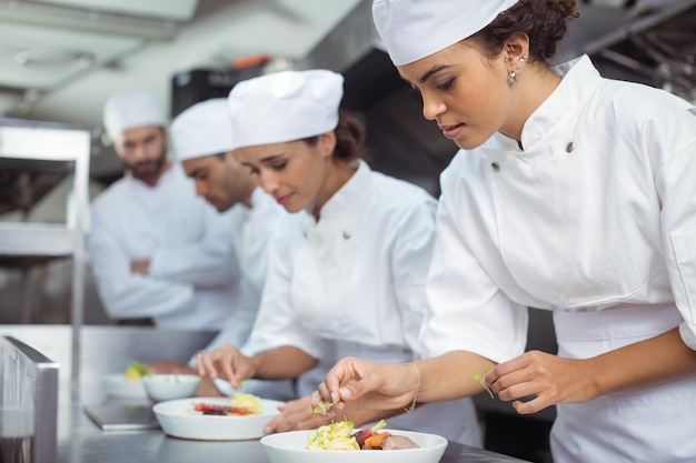 Female chef garnishing food in kitchen