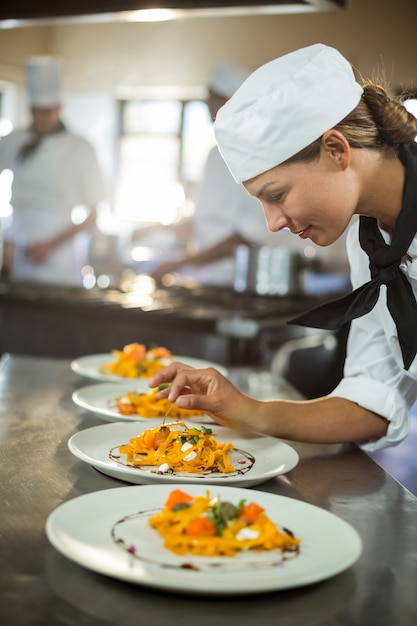 Cuoco unico femminile che guarnisce piatto di alimento