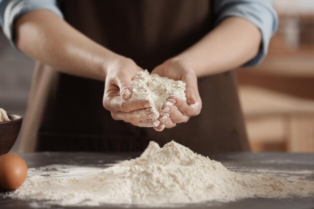 Foto cuoco unico femminile che tiene in mano la farina bianca in cucina