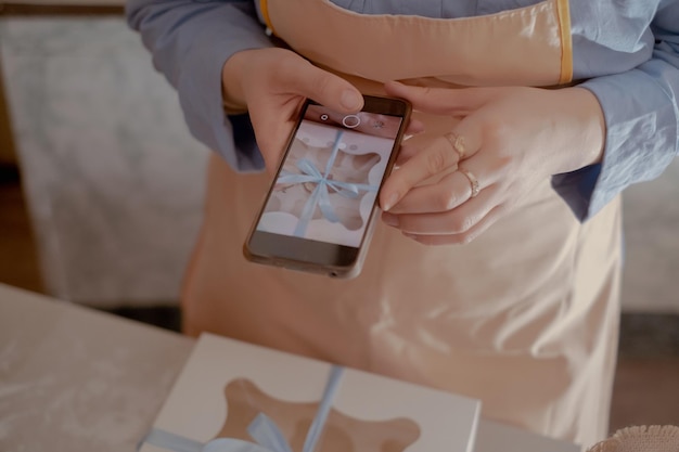 A female chef pastry chef takes photos on her mobile phone to advertise her business highlighting