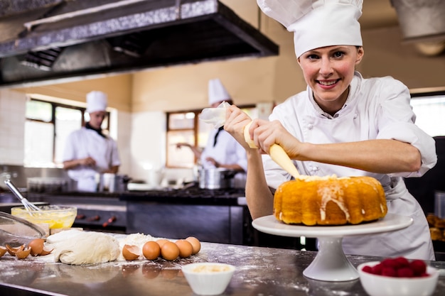 キッチンでケーキをパイピング女性シェフ