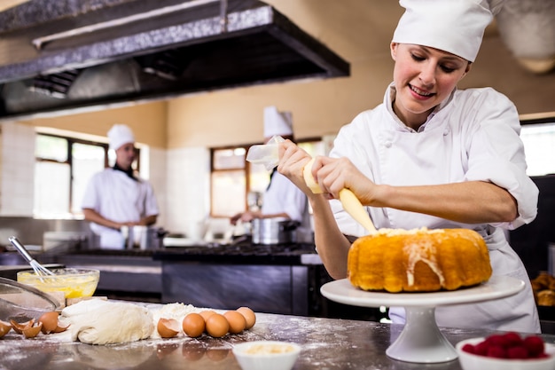 Cuoco unico femminile che convoglia un dolce in cucina