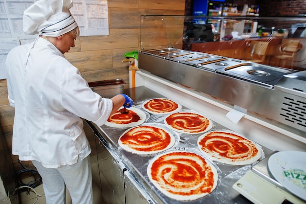 Female chef preparing pizza in restaurant kitchen.