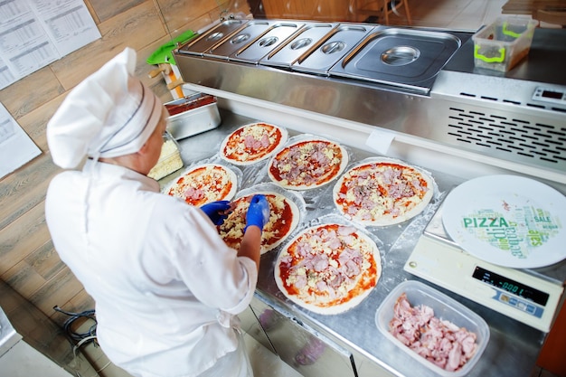 Female chef preparing pizza in restaurant kitchen.