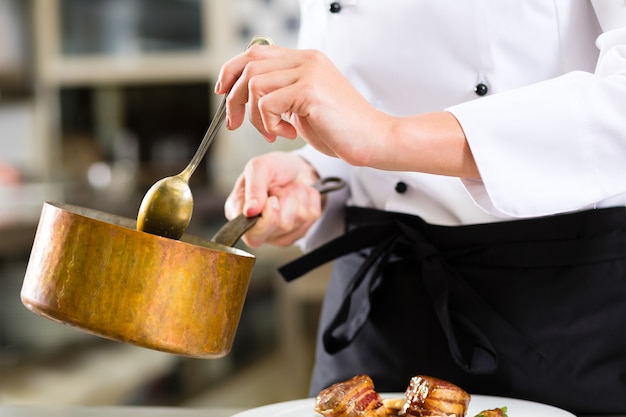 Cuoco unico femminile nella cottura della cucina del ristorante