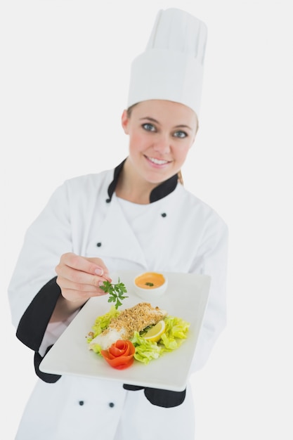 Female chef seasoning meal with parsley