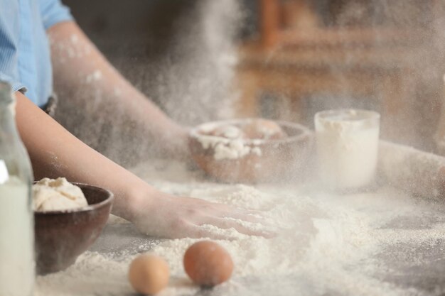 Foto cuoca con farina e ingredienti per l'impasto sul tavolo in cucina