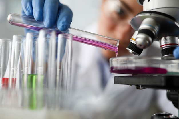 Female chemist holds test tube of glass in hand closeup