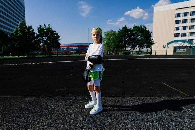 Female child boxer in gloves, feminism concept. Back to school, physical training lesson.