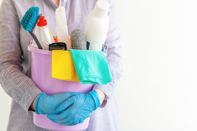 Female cleaner holding a bucket with cleaning supplies.