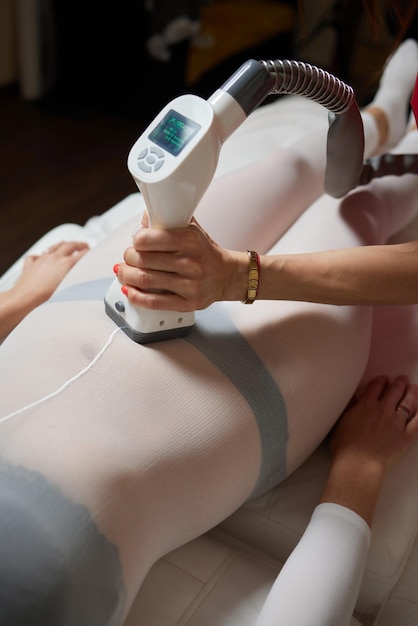 Photo female client in white suit lying an her tomach getting lpg massage in a spa