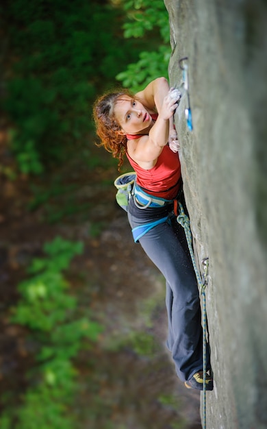 Female climber climbing steep rock, searching for next grip