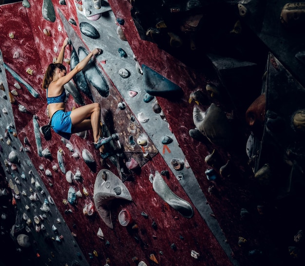 Female climber. Extreme indoor climbing. Side view.