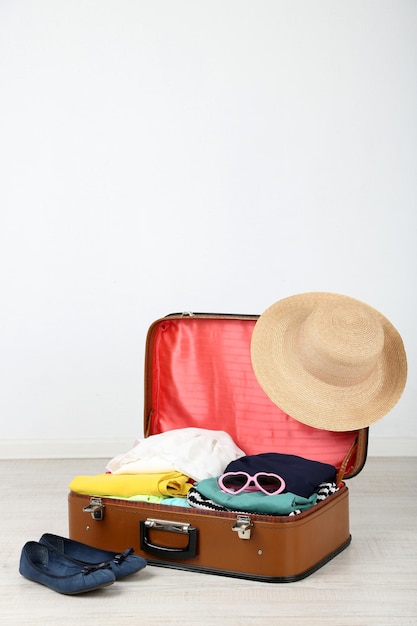 Female clothes in old suitcase on light background