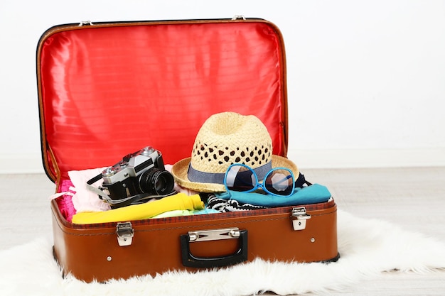 Photo female clothes and photo camera in old suitcase on light background