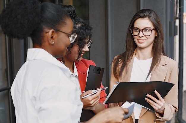 Colleghe che discutono i dati nella caffetteria all'aperto. donne multirazziali che analizzano la strategia produttiva per la proiezione aziendale utilizzando documenti in street cafe