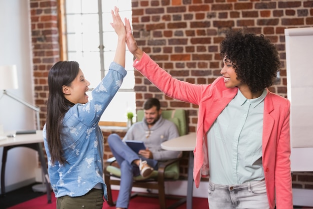 Female colleagues high fiving in office