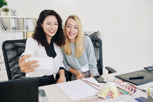 写真 セルフィーを取る女性の同僚