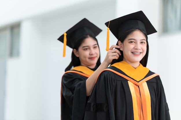 Laureate femminili che indossano cappelli neri, nappe gialle, sorridenti e felici il giorno della laurea