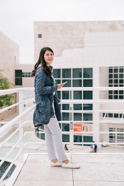 a female college student standing outdoor,chatting on cellphone and waiting her friend