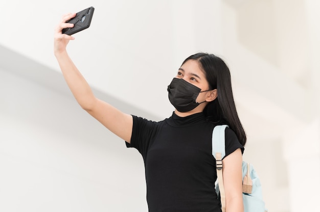 Una studentessa universitaria con un telefono che prende un selfie all'università, torna a scuola,