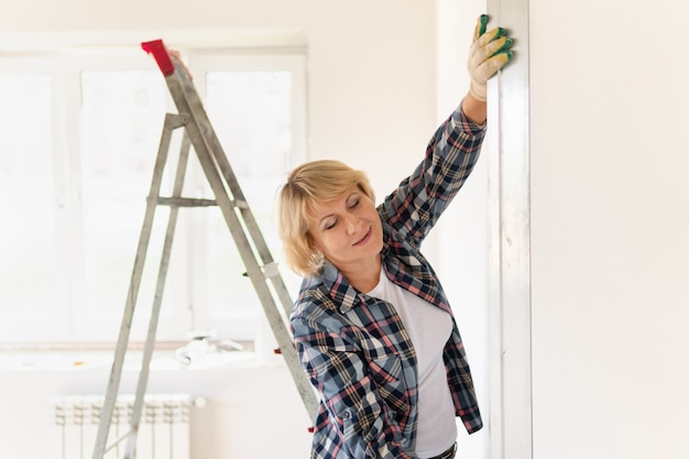 Female construction worker aligns the walls