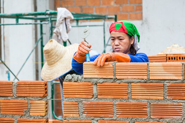 Female construction worker stacks terra cotta bricks to make wall at a construction site