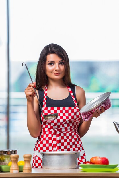 Female cook preparing soup in brightly lit kitchen