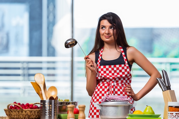 Female cook preparing soup in brightly lit kitchen