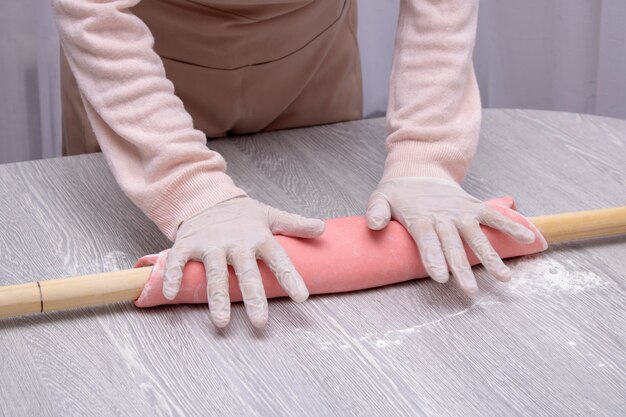 Female cook rolling dough with rolling-pin.
