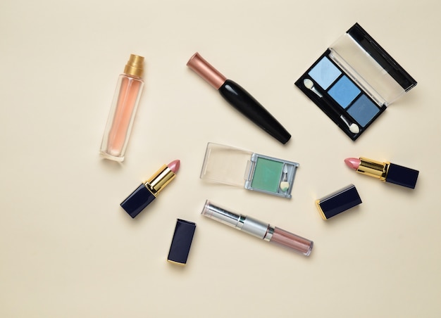 Female cosmetics for make-up layout. Cosmetic shadows, make-up brush, eyeshadow lipstick, perfume bottle. Flat lay, top view. Copy space.