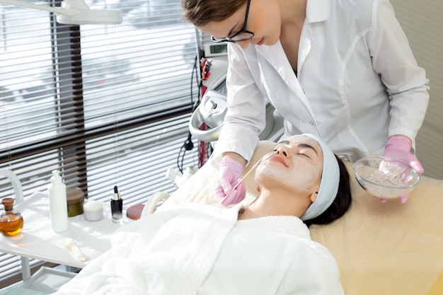 Female Cosmetologist Applying Face Mask