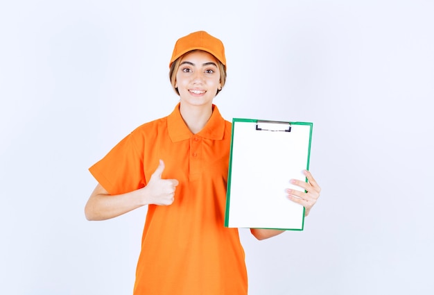 Corriere femminile in uniforme arancione che mostra un elenco di clienti e mostra un segno di soddisfazione