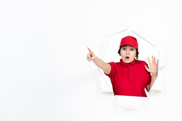 Female courier in red uniform pointing above on white