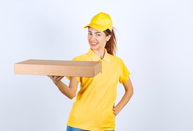 Female courier in yellow uniform delivered a cardboard parcel to the right address. 