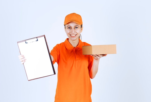 Женский курьер в желтой форме доставляет картонную коробку и представляет покупателю контрольный список.