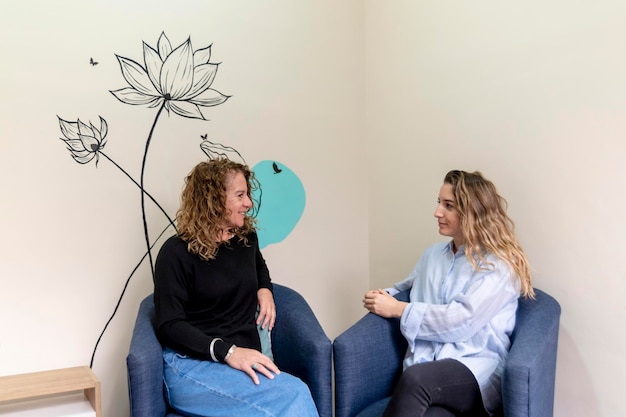 Female coworkers smiling while relaxing sitting on armchairs during a break at work