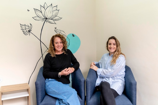 Female coworkers smiling while relaxing sitting on armchairs during a break at work