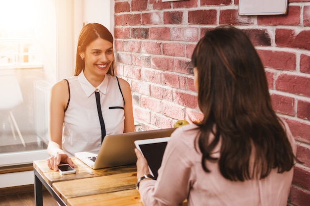 Female coworkers working together in bright office.