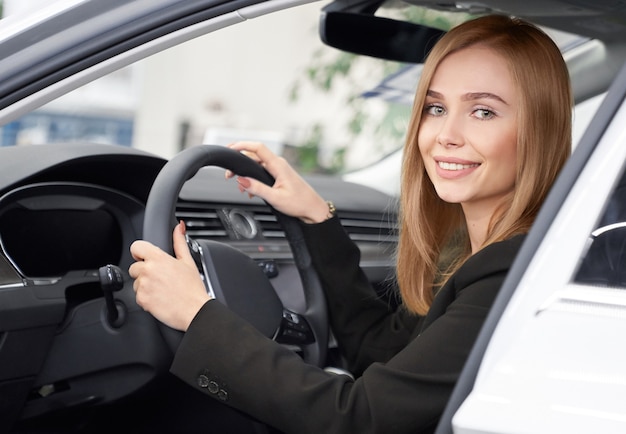 Female customer of auto salon sitting in white car