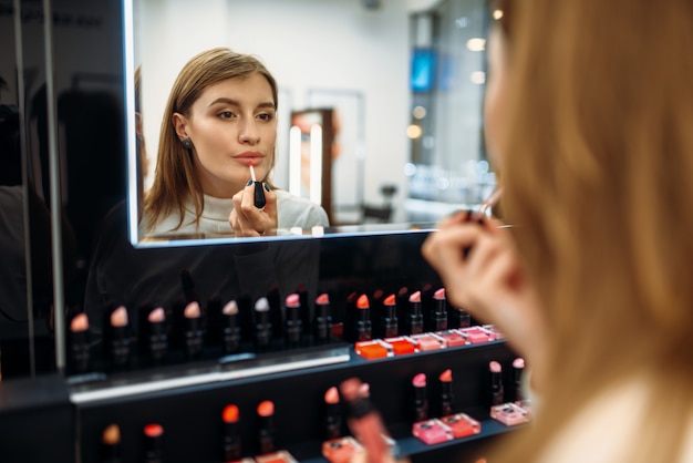 Female customer looks at the mirror in makeup shop