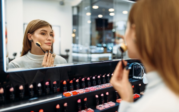 Female customer looks at the mirror in the makeup shop.