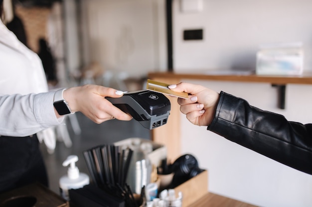 Female customer making wireless or contactless payment using credit card closeup of human hands