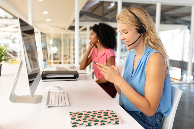 Photo female customer service executive using mobile phone at desk