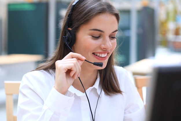 Female customer support operator with headset and smiling.