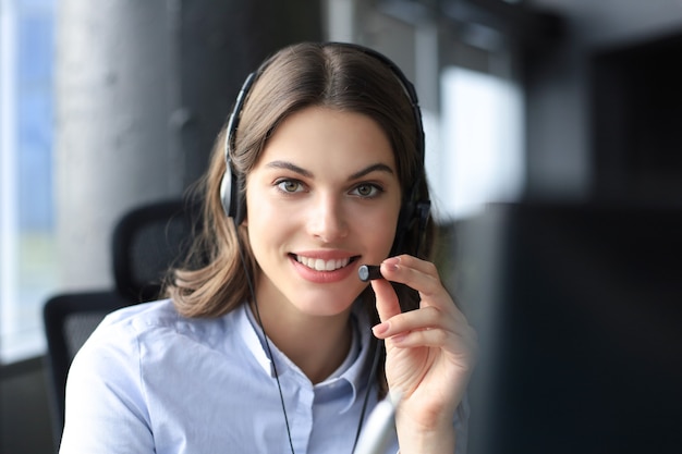 Female customer support operator with headset and smiling.