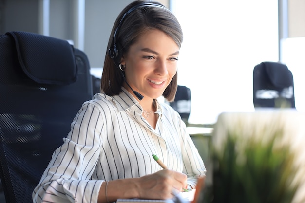 Female customer support operator with headset and smiling.