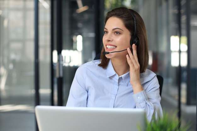 Female customer support operator with headset and smiling.