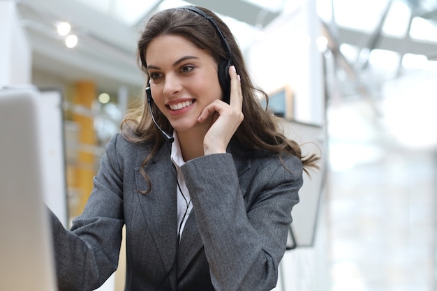 Female customer support operator with headset and smiling.