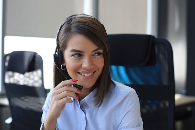 Female customer support operator with headset and smiling.